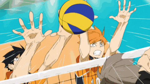 a group of volleyball players trying to block a ball