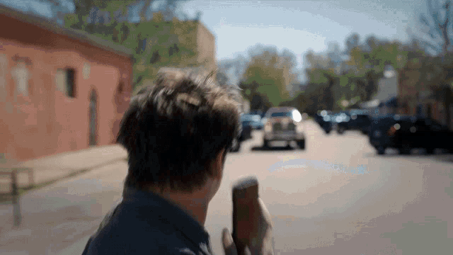 a man is walking down a street holding a bottle