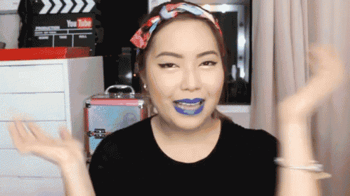 a woman wearing blue lipstick and a headband with a youtube sign in the background