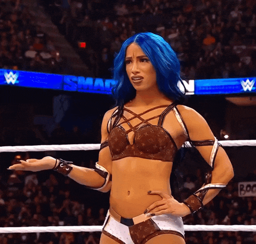 a woman with blue hair is in a wrestling ring with a sign that says smackdown in the background