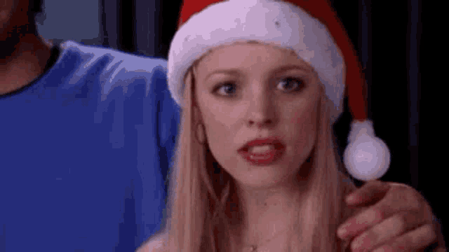 a woman wearing a santa hat and holding a lollipop .