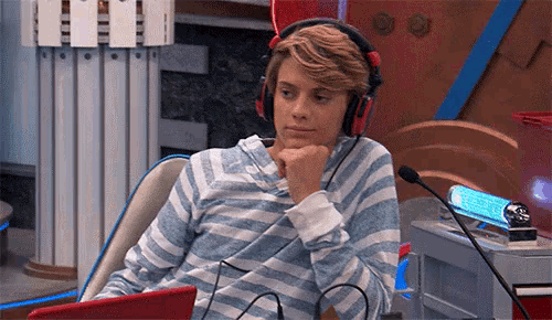 a young man wearing headphones sits in front of a microphone