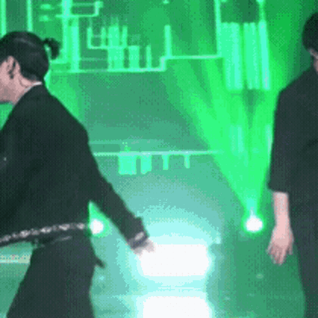 two people are dancing on a stage with green lights