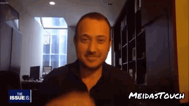 a man in a black shirt is smiling in front of a screen that says the issue is