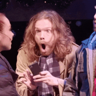 a man with a surprised look on his face is holding a cellphone