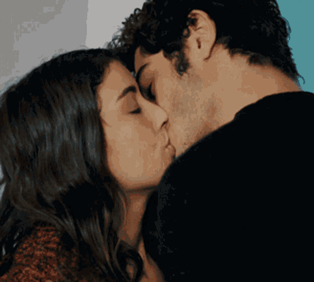 a man and a woman are kissing in a room