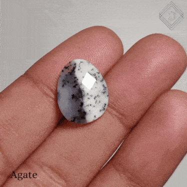 a close up of a person 's finger holding an agate