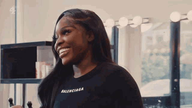 a woman wearing a black balenciaga t-shirt smiles