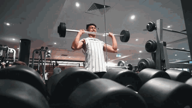 a man is lifting a barbell in a gym surrounded by dumbbells