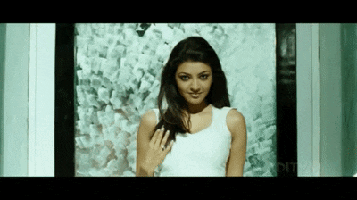 a woman in a white tank top is standing in front of a window .
