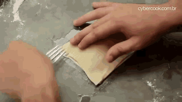 a person is cutting a piece of dough with a fork on a counter .