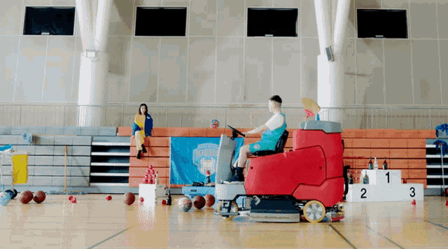 a man is riding a red machine on a basketball court in front of a blue banner that says ' blue devils '