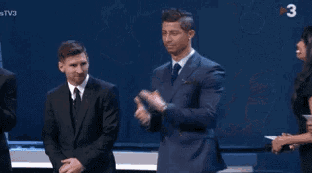 a man in a suit and tie is standing next to another man in a suit and tie on a stage .