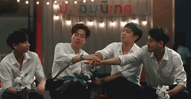 a group of young men are putting their hands together in front of a sign that says u auuna
