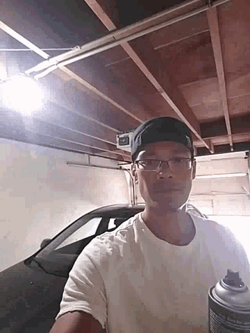 a man wearing glasses and a black hat is standing in a garage
