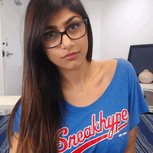 a woman wearing glasses is wearing a blue shirt that says sneakhype
