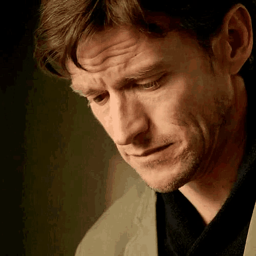 a man is looking down with a sad look on his face