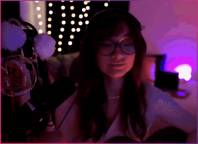 a woman wearing glasses and headphones stands in front of a microphone that says shure