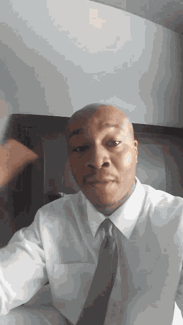 a man in a white shirt and tie is looking at the camera