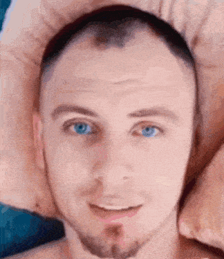 a man with blue eyes and a beard is smiling and looking at the camera