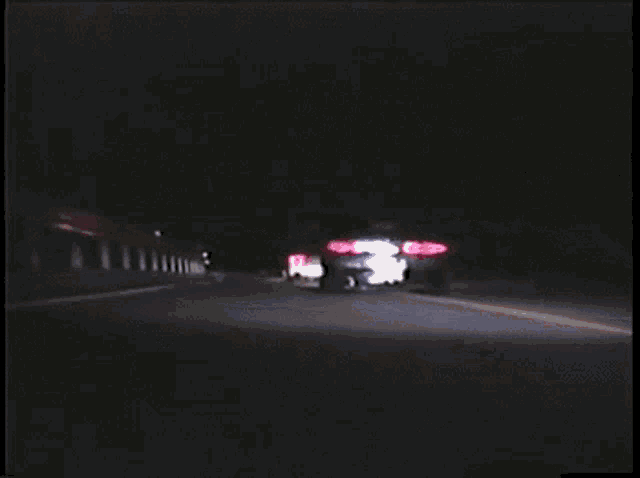 two cars are driving down a road at night and one has a license plate that starts with the letter a