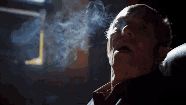 an older man is smoking a cigarette and the smoke is coming out of his mouth