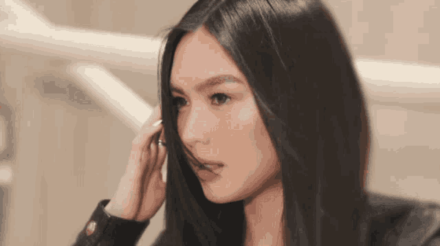 a close up of a woman 's face with her hand on her hair