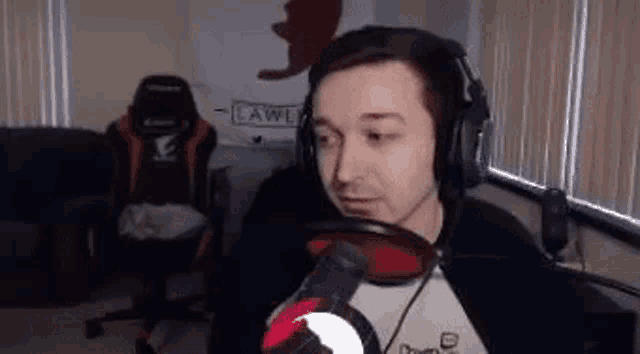 a man wearing headphones is standing in front of a microphone in a room .