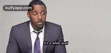 a man in a suit and tie is sitting down and talking .