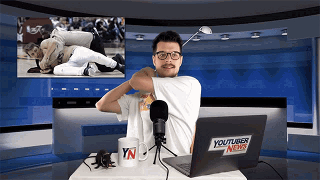 a man sitting in front of a laptop that says youtuber news on it