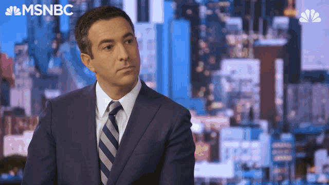 a man in a suit and tie is sitting in front of a screen that says msnbc