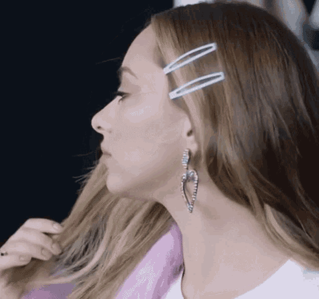 a close up of a woman 's face with hair clips in her hair and earrings .