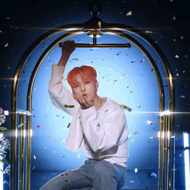 a man with pink hair blows a kiss while sitting in a hotel cart