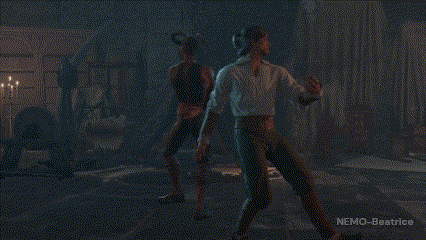 two people are dancing in a dark room with candles in the background .