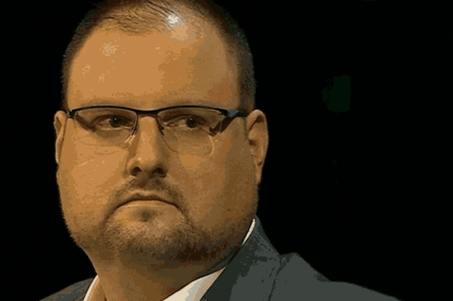 a man with a beard wearing glasses and a suit