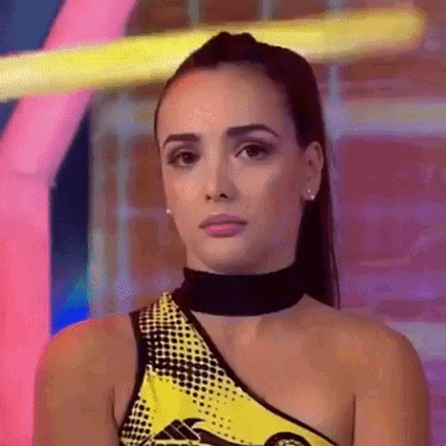 a close up of a woman wearing a yellow and black top and a choker .