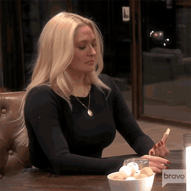 a woman is sitting at a table with a bowl of eggs and a sign that says bravo