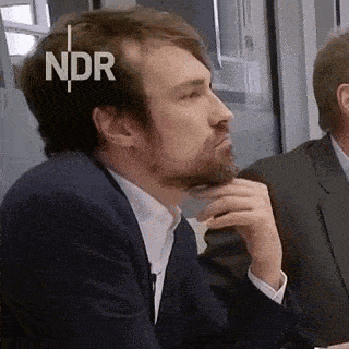 a man with a beard is sitting at a table with ndr written on his head
