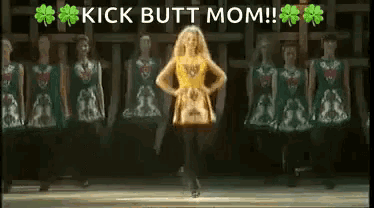 a woman in a yellow dress is dancing on a stage in front of a group of dancers .