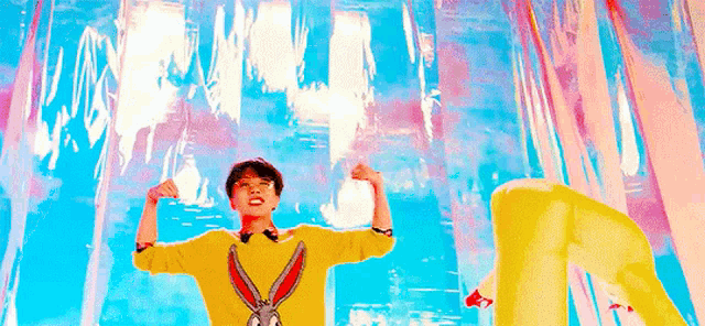 a man in a yellow bunny rabbit sweater is flexing his muscles in front of a colorful background .