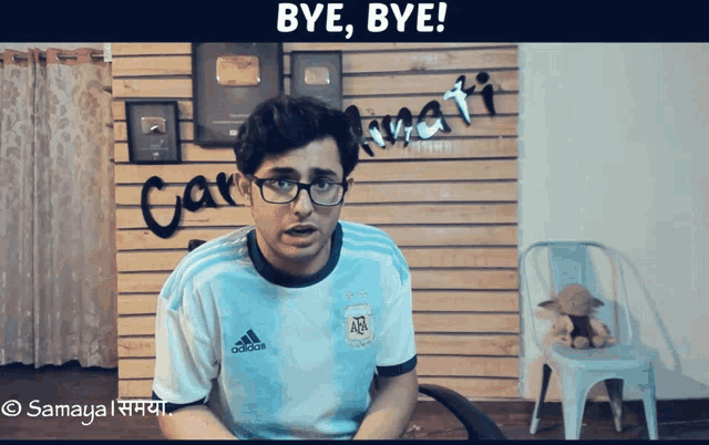 a man wearing an adidas shirt says bye bye in front of a wooden wall