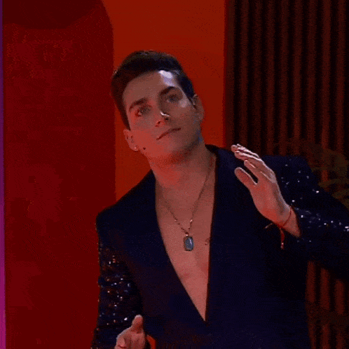 a man wearing a black jacket with sequins on the sleeves and a dog tag necklace