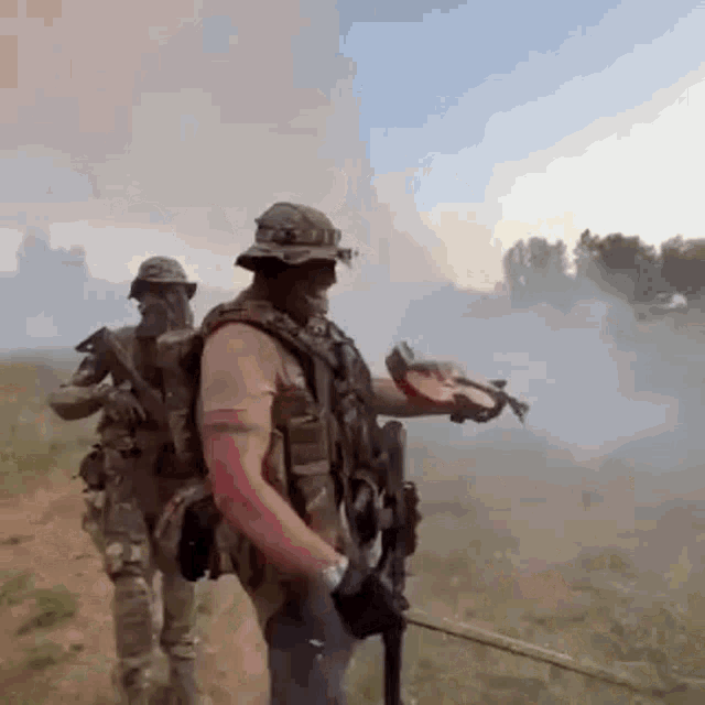 a group of soldiers are standing in a field with smoke coming out of it .