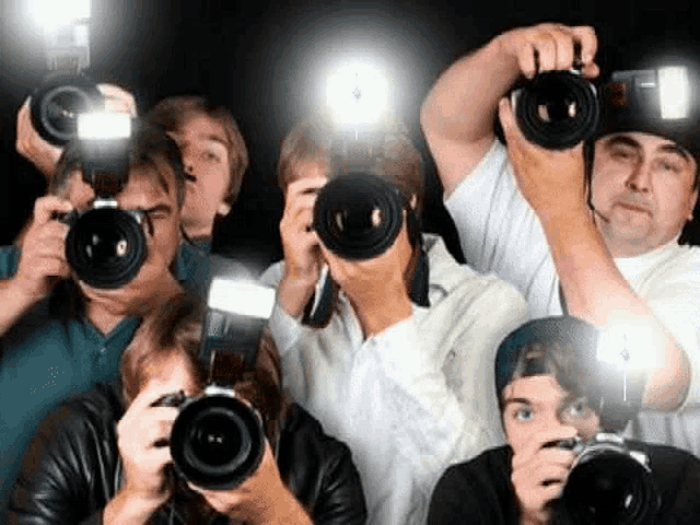 a group of people are taking pictures with their cameras in the dark .