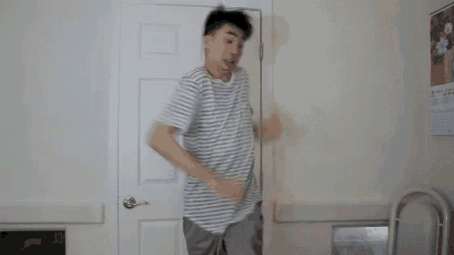 a man in a striped shirt is dancing in a room