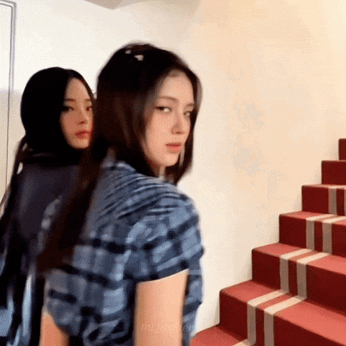 two women are standing next to each other on a set of stairs .