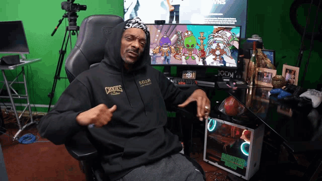 a man wearing a hoodie that says snoop dogg is sitting in front of a green screen