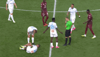 two men are playing soccer on a field and one of them is wearing a white jersey with a yellow g on it .