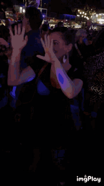 a woman is smiling in front of a crowd of people with a gif that says imgplay on the bottom right
