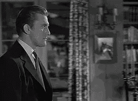 a man in a tuxedo and tie is standing in a room .